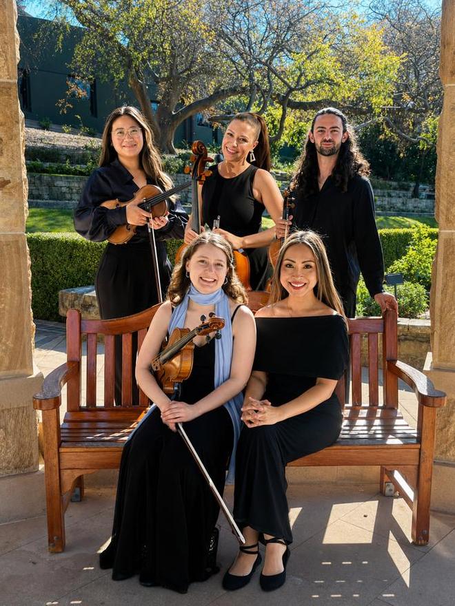Adlina and four string players in black, seated and standing around a garden bench